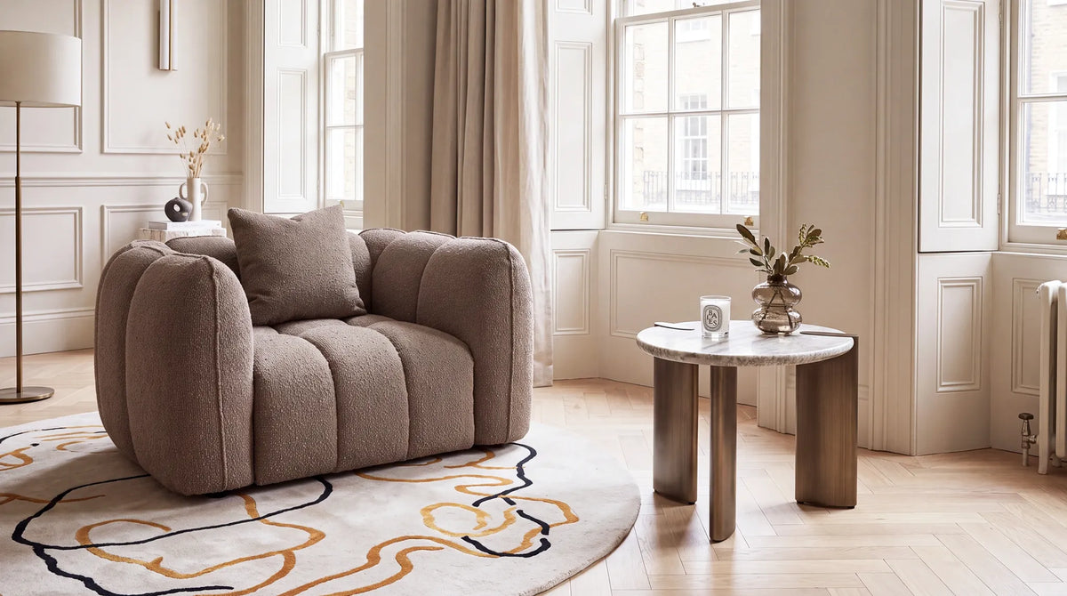 Richmond Interiors side table styled beside a curved armchair in a light contemporary living room